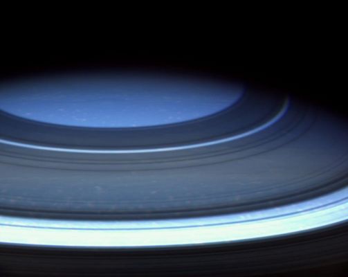 Saturn's Northern Hemisphere in natural colors
Caption NASA originale:"Saturn's Northern Hemisphere is presently a serene blue, more befitting of Uranus or Neptune, as seen in this natural color image from Cassini. 
Light rays here travel a much longer path through the relatively cloud-free upper atmosphere. Along this path, shorter wavelength blue light rays are scattered effectively by gases in the atmosphere and it is this scattered light that gives the region its blue appearance. Why the upper atmosphere in the northern hemisphere is so cloud-free is not known, but may be related to colder temperatures brought on by the ring shadows cast there. 
Shadows cast by the rings surround the pole, looking almost like dark atmospheric bands. The ring shadows at higher latitudes correspond to locations on the ringplane that are farther from the planet - i.e.: the northernmost ring shadow in this view is made by the outer edge of the A-Ring. 
Spots of bright clouds also are visible throughout the region. This view is similar to an infrared image obtained by Cassini at nearly the same time".
Parole chiave: Saturn