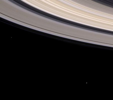 Saturn, Janus and Mimas (in natural colors)
Caption NASA originale:"Looking something like the fibrous bow of a violin, Saturn's colorful rings sweep through this spectacular natural color view while two small moons look on. 
From left, the moons visible here are Janus (181 Km across) and Mimas (398 Km across). Cassini's view in this image is from beneath the ring plane; the moons are on the far side of Saturn. Janus leads Mimas as the two moons orbit the planet. Nearly the entire ring system can be seen in this view. The diaphanous C-Ring appears at the upper right, followed by the multi-hued B-Ring. Next, the famous Cassini division (4.800 Km wide) separates the A and B rings. The outer edge of the B-Ring which forms the inner boundary of the Cassini division is maintained by a gravitational resonance with Mimas. Near the outer edge of the A-Ring are the Encke Gap (325 Km wide) and the barely visible Keeler Gap (35 Km wide). The faint, thread-like F-Ring is slightly discernible just beyond the main rings". 
Parole chiave: Saturn and Company