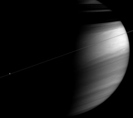 Like a light in the darkness: Dione
This moody portrait of Saturn captures a razor-thin Ring-Plane bisecting the clouds of the bright Equatorial Region. The Rings cast dark, shadowy bands onto the Planet's Northern Latitudes. 
At left, Dione is a tiny sunlit orb against the Planet's Dark Side. 

The image was taken in polarized infrared light with the Cassini spacecraft wide-angle camera on Dec. 7, 2005 at a distance of app.x 3,1 MKM (about 1,9 MMs) from Saturn and at a phase angle of 96°. Image scale is 179 Km (about 111 miles) per pixel. 

Parole chiave: Saturn and Dione