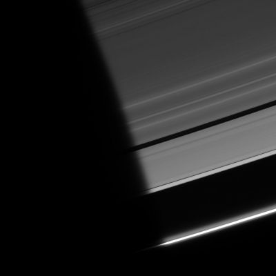 Out of the Dark...
Caption NASA:"As Ring particles emerge from the darkness of Saturn's shadow, they pass through a region of twilight. The Sun's light, refracted by the Planet's atmosphere, peeks around the limb, followed shortly by the Sun itself. 
The "penumbra" is the narrow fringe Region of the Planet's shadow where part (but not all) of the Sun is visible around the side of the Planet, creating only a partial shadow there and making the shadow edge look fuzzy. 

The A and F-Rings are captured here. This view looks toward the unlit side of the Rings from about 20° above the Ring-Plane. Two faint ringlets can be seen within the Encke Gap, which stretches out of the blackness at center and toward right. 

The image was taken in visible light with the Cassini spacecraft narrow-angle camera on Sept. 12, 2006 at a distance of approx. 1,5 MKM (about 900.000 miles) from Saturn and at a phase angle of 163°. Image scale is roughly 9 Km (about 5 miles)".
Parole chiave: Postcard from Saturn