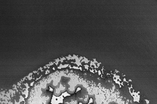 South Polar "Shoreline" (Original NASA/MGS/MSSS b/w Frame)
Caption NASA originale:"This MGS-MOC image shows the very edge of the South Polar Residual Cap of Mars. The bright areas, which appear somewhat like pieces of sliced "Swiss cheese", are composed mainly of frozen Carbon Dioxide. The Scarps around the edges of the Carbon Dioxide mesas have been retreating at a rate of roughly 3 mt (~3 yards) per Martian Year; in this case, exposing a darker surface that lies below".

Location near: 85,4° South; 88,6° West
Image width: ~3 km (~1,9 mi)  
Illumination from: upper left  
Season: Southern Summer
Parole chiave: Mars from orbit - South Polar Features - Residual Cap