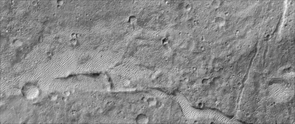 Aram Chaos
Aram Chaos is thought to be a degraded impact crater that was once filled with water and sedimentary units. The term "chaos" refers to the cracks and angled blocks formed perhaps by withdrawl of subsurface material. This sub-image covers only a small portion of Aram Chaos and illustrates the modification of the crater by fracturing, younger impact craters, and wind. A linear fracture cuts through the center of the image while a more sinuous depression filled with bright ripples or dunes is located towards the bottom of the image. Both depressions could have resulted from collapse associated with modification of the impact crater that created Aram Chaos or later disruption when water and sediment covered some of the crater floor. Impact craters of many shapes and sizes can be seen across the image, indicating a relatively older surface that has seen little modification since its formation. The bright ripples or dunes appear to cluster in low-lying topography, such as the sinuous depression and a larger impact crater in the lower right of the image, suggesting that wind has moved fine material along the surface until it becomes trapped in low spots where it collects to form ripples or dunes. 


Parole chiave: Mars from orbit - Aram Chaos Region