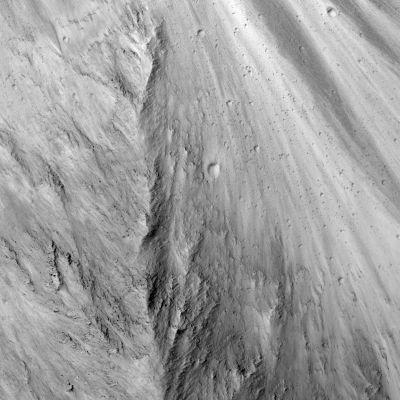 Candor Chasma
This HiRISE sub-image shows the steep slopes along wallrock in the eastern edge of West Candor Chasma. In general, the rocks in the upper part of the canyons are interpreted to be lava flows that cover the plains surrounding Valles Marineris, whereas the deeper material along the walls could be either more lava flows or megaregolith that resulted from numerous impact craters that disrupted the Martian surface during the first billion years after formation of the planet. Resistant material is visible in portions of the sub-image and HiRISE is able to resolve 1-2 meter size boulders shedding out of these resistant wallrock units. The bright and dark lineations seen in the right of the sub-image follow the slope of the wallrock (downslope is towards the top of the sub-image) and likely represent bright dust and dark sand that are sliding downslope. The large number of small impact craters visible along the slopes indicates that there isn't a large amount of material moving downslope recently because these craters would have been destroyed or buried. 


Parole chiave: Mars from orbit - Candor Chasma (Valles Marineris T.S.) Region