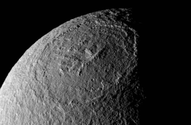 Odysseus
Original caption:"Plunging cliffs and towering mountains characterize the gigantic impact structure called Odysseus on Saturn's moon Tethys. The great impact basin lies before the Cassini spacecraft in one of the best views yet obtained. 
Quite a few small craters are visible inside Odysseus (450 Km - or 280 miles across), making it clear that this is not a very young structure. However, a comparison of cratering density between the interior of Odysseus and the surrounding terrain should show whether the large basin is at least relatively young. 
Odysseus lies on the Leading Hemisphere of Tethys; North is up and rotated 18° to the right. 

The image was taken in polarized ultraviolet light with the Cassini spacecraft narrow-angle camera on Dec. 24, 2005 at a distance of approx. 196.000 Km (about 122.000 miles) from Tethys and at a Sun-Tethys-spacecraft, or phase, angle of 85°. Resolution in the original image was about 1 Km (3,831 feet) per pixel. The image has been magnified by a factor of two and contrast-enhanced to aid visibility".
Parole chiave: Saturn's Moons - Tethys