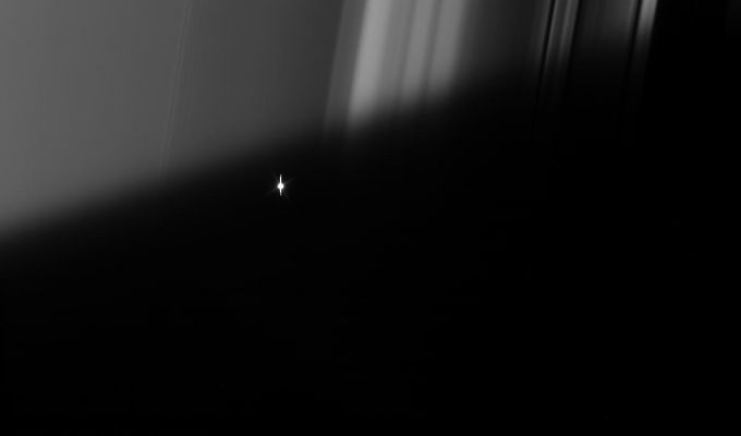 Not the Sun, but Aldebaran!
Caption NASA originale:"Cassini took a series of images on Sept. 9, 2006 as it watched the bright red giant star Aldebaran slip behind Saturn's Rings. 
This type of observation is known as a "stellar occultation" and uses a star whose brightness is well known. As Cassini watches the rings pass in front, the star's light fluctuates, providing information about the concentrations of ring particles within the various radial features in the Rings. 
Here, Cassini watches the star through the part of the Rings masked by Saturn's shadow. The view looks toward the sunlit side of the Rings from about 20° below the Ring-Plane. Bright Aldebaran is over exposed, creating thin vertical lines ("effetto goccia") on its image. 

The image was taken in visible light with the Cassini spacecraft narrow-angle camera on Sept. 9, 2006 at a distance of approx. 351.000 Km (such as about 218.000 miles) from Saturn. Image scale on the sky at the distance of Saturn is 2 Km (a little more than 1 mile) per pixel".
Parole chiave: Aldebaran