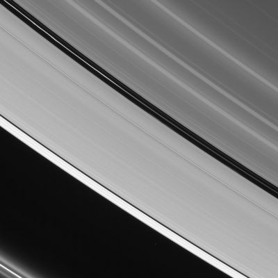 What's inside the Rings?
The 2 prominent dark gaps in Saturn's A-Ring contain small embedded moons and a host of other intriguing features. Here, 3 unique ringlets are visible in the Encke Gap (about 325 Km wide). The innermost ringlet (topmost here) is faint but continuous. The center ringlet brightens substantially toward upper left and displays a few slight kinks. This ringlet is coincident with the orbit of Pan (about 26 Km across). The outermost ringlet is discontinuous, with two bright regions visible. 
The narrower Keeler Gap (about 42 Km wide) hosts the moon Daphnis (7 Km across - not visible in this image), which raises waves in the Gap edges as it orbits Saturn. At lower left, faint ringlets flanking the bright F-Ring core are visible. These features were found by the Cassini spacecraft to be arranged into a spiral arm structure that winds around the Planet like a spring. The spiral may be caused by tiny moonlets or clumps of material that have smashed through the F-Ring core and liberated material.
This view looks toward the unlit side of the rings from about 23 degrees above the ringplane. 

The image was taken in visible red light with the Cassini spacecraft narrow-angle camera on Sept. 11, 2006 at a distance of approximately 1.1 million kilometers (700,000 miles) from Saturn and at a Sun-Saturn-spacecraft, or phase, angle of 151 degrees. Image scale is about 6 kilometers (4 miles) per pixel.

Parole chiave: Saturn's Rings - The Encke and Keeler Gaps and relevant "Ringlets"