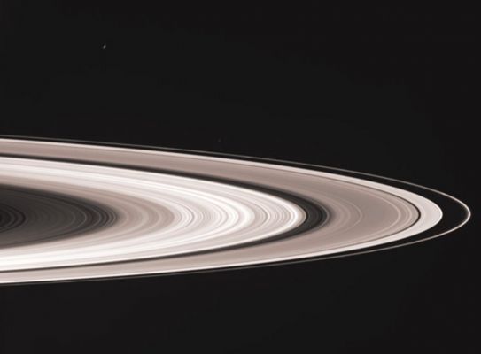 The Rings (in natural colors)
Caption NASA:"Saturn's sunlit Rings gleam in the blackness as two icy moons cruise past in the foreground. 
Enceladus is a small crescent near upper left; Janus is a speck above the F-Ring, near center. Janus was brightened slightly for visibility. 
This view looks toward the lit side of the Rings from about 5° below the Ring-Plane. 

This image was taken in visible red light with the Cassini spacecraft wide-angle camera on Nov. 7, 2006, at a distance of approx. 1,1 MKM (about 700.000 miles) from Saturn and at a Sun-Saturn-Spacecraft, or phase, angle of 139°. 
Image scale on the sky at the distance of Saturn is roughly 63 Km (about 39 miles) per pixel".
Parole chiave: Saturn's Rings