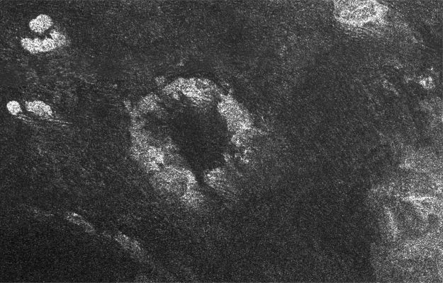 Guabonito Crater
This image of Saturn's moon Titan from the Synthetic Aperture Radar Instrument on the Cassini spacecraft shows the South-Western area of a feature called Xanadu (bottom right of the image). The area is bright because it reflects the radio wavelengths used to make this radar images and this image was taken on April 30, 2006. Xanadu is one of the most prominent features on Titan and was first seen in ground-based observations. The origin of Xanadu is still unknown, but this radar image reveals details previously unseen, such as numerous curvy features that may indicate fluid flows. Linear dark streaks visible in radar-dark areas are dune fields, also seen in previous radar images.
Near the center of the image is a prominent circular feature, named Guabonito, about 90 Km (about 56 miles) in diameter. It might be an impact crater or a cryovolcanic caldera. If this is an impact structure, the absence of an ejecta blanket suggests that the feature has been highly eroded, like some impact structures on Earth, or has been buried by the dune fields. Other radar-bright areas (top left and top right) appear to be topographically high and might act as obstacles, diverting the dunes around them".
Parole chiave: Saturn's Moons - Titan