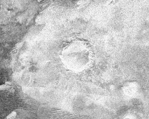 Impact Crater on Titan (radio-image)
Caption NASA originale:"This image shows a crater, approx. 60 Km in diameter, on the very eastern end of the radar image strip taken by the Cassini orbiter on its third close flyby of Titan on Feb. 15, 2005. 
The appearance of the crater and the extremely bright (hence rough) blanket of material surrounding it is indicative of an origin by impact, in which a hypervelocity comet or asteroid, in this case, roughly 5-10 Km, in size, slammed into the surface of Titan. The bright surrounding blanket is debris, or ejecta, thrown out of the crater. The asymmetric appearance of this ejecta blanket could be an effect of "atmospheric winds" associated with the impact itself. Although clearly formed by impact, the feature lacks a central peak, suggesting that it has been eroded or otherwise modified after formation. Rainfall, wind erosion and softening of the solid material in which the crater formed are all possible processes that might have altered this impact feature".
Parole chiave: Saturn's Moons - Titan