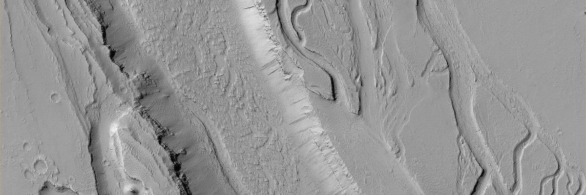 Troughs System in Olympica Fossae (Original NASA/MGS/MSSS b/w Frame)
Caption NASA originale:"This MGS-MOC image shows a wide, flat-floored Trough flanked by several smaller, branching Troughs in the Olympica Fossae Region of Mars. Dark and intermediate-toned Slope Streaks —both created by dry Avalanches of Dust — occur on the Trough Walls".

Location near: 25,1° North; 113,8° West
Image width: ~3 Km (~1,9 mi)  
Illumination from: lower left  
Season: Northern Winter
Parole chiave: Mars from orbit - Troughs - Olympica Fossae