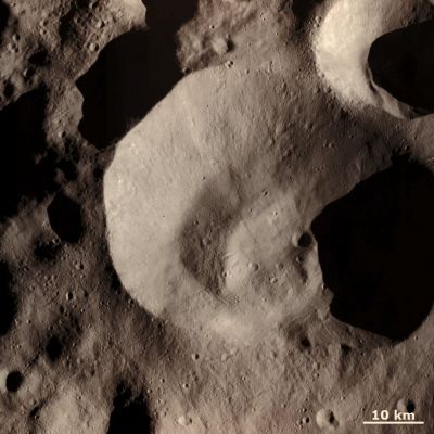 Caparronia Crater and Surroundings (Natural Colors; credits for the additional process. and color.: Dr Paolo C. Fienga - Lunexit Team)
This Dawn FC (framing camera) image is dominated by Caparronia Impact Crater. Caparronia Crater is approximately 55 Km in diameter and has a mostly fresh, irregularly shaped Rim. It also has a curved, linear mound running across most of its base. For all of these reasons Caparronia is a distinctive Crater and this is why it was chosen to name the Quadrangle in which it is situated. The smooth region around Caparronia Crater is most likely fine Impact Ejecta, which were thrown out from the Crater at the time of its formation. Other impact related features are the linear chains of small, less than 1 km wide, Secondary Craters that occur throughout the image. Some particularly distinctive Crater Chains are in the bottom part of the frame. 
Secondary Crater Chains are formed when relatively large debris are ejected from an impact and skip along the Surface, much like a stone skipping across a lake. There are also some linear scars running diagonally across the image, which are due to debris scouring across the Surface. 

This image is centered in Vesta's Caparronia Quadrangle and the center Latitude and Longitude of the image is 52,5° North and 149.2° East. NASA's Dawn Spacecraft obtained this image with its framing camera on October 23rd 2011. This image was taken through the camera's clear filter. The distance to the Surface of Vesta, at the time the picture was taken, was approx. 700 km and the image has a resolution of about 70 meters per pixel. This image was acquired during the HAMO (High Altitude Mapping Orbit) phase of the mission.
Parole chiave: Asteroids - 4 Vesta