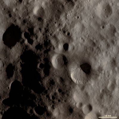Fabia Crater and Surroundings (Absolute Natural Colors; credits for the additional process. and color.: Dr Paolo C. Fienga - Lunar Explorer Italia - Italian Planetary Foundation)
This Dawn framing camera (FC) image of Vesta shows Fabia crater, which is the large crater offset to the bottom right of the center of the image. Fabia crater is very distinctive because the two sides of its rim have very different states of freshness. In this image the bottom part of the rim is distinct and fresh but the top part of the rim is much more rounded and degraded. This dichotomy between the rims is possibly due to material slumping over the top part of Fabia's rim, which caused the rim to become obscured and look more degraded. There are linear features visible on the illuminated part of Fabia crater, which were probably created by material cascading towards the center of the crater. There is also a distinguishing band of bright material along the bottom rim of the crater. 

This image is located in Vesta's Numisia quadrangle, in Vesta's northern hemisphere. NASA's Dawn spacecraft obtained this image with its framing camera on Oct. 19, 2011. This image was taken through the camera's clear filter. The distance to the surface of Vesta is 700 kilometers (435 miles) and the image has a resolution of about 63 meters (207 feet) per pixel. This image was acquired during the HAMO (high-altitude mapping orbit) phase of the mission. 

Parole chiave: Asteroids - 4 Vesta