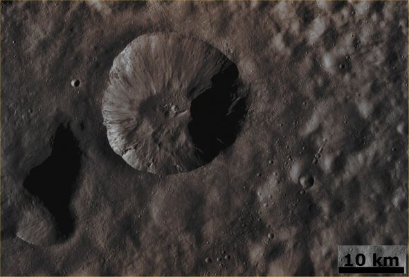 Unnamed Crater in Floronia Quadrant (Absolute Natural Colors; credits for the additional process. and color.: Dr Paolo C. Fienga - Lunexit Team)
This Dawn FC (framing camera) image is dominated by an approx. 20 Km-wide, young, fresh Unnamed Impact Crater. Surrounding this Unnamed Crater is its Ejecta Blanket, which is a covering of small particles that were thrown out during the impact that formed it and the Ejecta Blanket is the cause of the smooth Surface visible all around the Crater itself. This Ejecta Blanket buried many older, degraded craters, but some of them can be seen poking through the Blanket. Old and degraded craters are less clear or not visible directly next to the Unnamed Crater dominating the frame and this suggests that its Ejecta Blanket is very thick and fit to bury almost all the other (relatively small) impact craters located next to the bigger one. 

There are also several distinctive Chains of small Craters running obliquely across the image on top of the Ejecta Blanket. They were not buried by the Ejecta Blanket and this means that they must be younger than it. These Crater Chains likely formed due to Secondary Impacts, when material thrown out of previous impacts re-impacted Vesta. Similarly, material ejected from the Unnamed approx. 20 Km-wide Crater has fallen back into the Crater itself and created several Pit-like features on its Floor.

This image is in Vesta's Floronia Quadrangle and the center latitude and longitude of the image is 32,5° North and 1,2° East. NASA's Dawn Spacecraft obtained this image with its framing camera on October 24th, 2011. This image was taken through the camera's clear filter. The distance to the Surface of 4-Vesta is 662 Km and the image has a resolution of about 62 meters per pixel. This image was acquired during the HAMO (High Altitude Mapping Orbit) phase of the mission.
Parole chiave: Asteroids - 4 Vesta