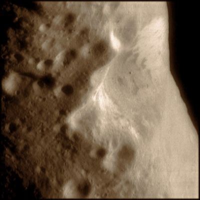 Oblique view of the "Large Crater" (natural colors; credits: Lunexit)
This image, showing an oblique view of Eros' "Large (central) Crater", was taken at a resolution of about 20 meters (65 feet) per pixel. The brightness or albedo patterns on the walls of this crater are clearly visible, with the brighter materials near the tops of the walls and darker materials on the lower walls. Boulders are seen inside this crater and the smaller nearby craters. The higher density of craters to the left of the large crater implies that this region is older than the smoother area seen associated with the Saddle Region on the opposite side of the asteroid. 

(Image 0127591846)
Parole chiave: Asteroids - 433-Eros