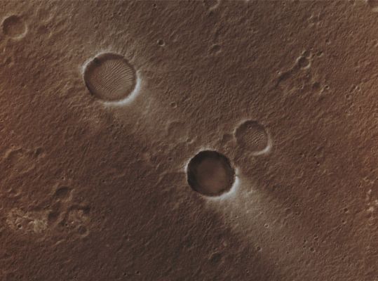 Windstreaks in Chryse Planitia (Natural Colors; credits for the additional process. and color.: Dr Paolo C. Fienga - Lunexit Team)
Caption NASA originale:"This MGS-MOC image shows two Unnamed Impact Craters of nearly equal size, plus their associated Windstreaks. These occur in far Eastern Chryse Planitia. The Wind streaks point toward the South-West, indicating that the responsible Winds blew from the North-East. One of the two craters is shallower than the other and has a suite of large, windblown Ripples on its Floor. The shallower Unnamed Crater with the Ripples is probably older than the other, deeper Unnamed Crater". 

Location near: 20,6° North Lat. and 30,1° West Long.
Image width: ~3 Km (~1,9 mi) 
Illumination from: lower left 
Season: Northern Winter 
Parole chiave: Mars from orbit - Craters - Unnamed Craters - Chrise Planitia Region