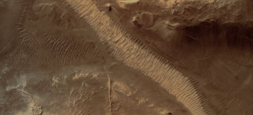 Auqakuh Vallis: "Old Riverbed" or "Windblown Ripples"? (Natural Colors; credits for the additional process. and color.: Dr Paolo C. Fienga - Lunar Explorer Italia)
Caption NASA originale:"This MGS-MOC image shows windblown ripples on the floor of Auqakuh Vallis. 
The light-toned area, running diagonally across the scene from South-West to North-East, may be dust that has accumulated in the bottom of the valley and on top of the ripples". 

Location near: 31,3° North; 299,3° West
Image width: ~3 Km (~1,9 mi) 
Illumination from: lower left 
Season: Northern Spring
Parole chiave: Mars from orbit - Channels - Auqakuh Vallis