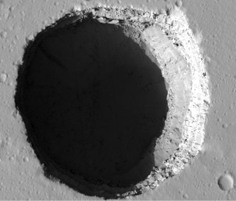 Collapse Pit in Tractus Fossae
This HiRISE image shows a Collapse Pit in Tractus Fossae, a Region of large ridges and troughs created by tectonic activity. 
The "Fossae" occur on the Tharsis Volcanic Rise, a giant Region of enhanced volcanic activity that includes the three large volcanoes Ascraeus Mons, Pavonis Mons and Arsia Mons. 
The Pit in this image has very steep walls, and so only a narrow arc is illuminated by Sunlight. The rest of the Pit is in dark shadow. However, a stretched version of the image shows details of the pit floor, due to a small amount of scattered Sunlight.

Pits like this form by collapse into underground voids, such as those left by propagating magma-filled dikes. They may sometimes have overhanging walls, although in this case the walls can be seen and appear nearly vertical. Some similar features are found on Earth: Devils Throat, in Hawaii, is one example. Other similar examples have been imaged on Mars as well.
Parole chiave: Mars from orbit - Collapse Features - Pit