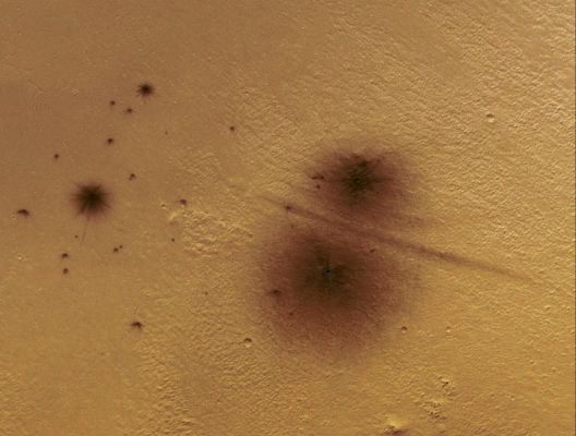 Recent Double-Impact (edm - possible Natural Colors; credits: Lunar Explorer Italia)
The MRO Context Imager (CTX) team has been discovering many new impact events on Mars, and then they request HiRISE follow-up imaging to confirm an impact origin and to identify and measure the craters.

Crater clusters are common as these small (typically less than 1 meter diameter) objects break up in the thin Martian air and separate a little bit to make crater clusters up to a few hundred meters wide. The example shown here is the result of an impact that occurred between May 2003 and September 2007. 
It was first discovered as a dark spot in a CTX image acquired in March 2008, but later found to be partly visible at the very edge of a CTX image acquired in September 2007. 

A dark spot is not present in the previous image of this location with sufficient resolution to have detected it, acquired by the visible THEMIS camera on Mars Odyssey in May 2003. Thus the impact might have formed anytime between May 2003 and September 2007. The dark markings are created by removing or disturbing the surficial dust cover, and so far new impact sites have been discovered only in dust-covered regions of Mars. 

Although small Martian crater clusters are common, this example is unusual because there is a dark line between the two largest craters. We hypothesize that atmospheric breakup coincidentally made two nearly equal-size objects that impacted close together in space and time so the air blasts interacted with each other to disturb the dust along this line. 

Hundreds of these small objects (mostly asteroid fragments) impact Mars per year. A comparable number of small objects impact Earth each year, but explode in the upper reaches of our atmosphere and have no effect on the surface, fortunately for those of us who live here.
Parole chiave: Mars from orbit - Craters - Unnamed Fresh Double-Crater