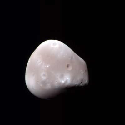 Deimos (Natural - but enhanced - Colors; credits: NASA/JPL/Univ. of Arizona)
HiRISE captured this enhanced-color image of Deimos, the smaller of the two moons of Mars, on 21 February 2009. 
Deimos has a smooth surface due to a blanket of fragmental rock or regolith, except for the most recent impact craters. It is a dark, reddish object, very similar to Phobos.
There are subtle color variations — redder in the smoothest areas and less red near fresh impact craters and over ridges or topographic highs (relative to its center of gravity).

These color variations are probably caused by the exposure of surface materials to the space environment, which leads to darkening and reddening. Brighter and less-red surface materials have seen less exposure to space due to recent impacts or downslope movement of regolith.
With an image scale of about 20 mt/pixel, features 60 mt or larger can be discerned.
Parole chiave: Mars' Moons - Deimos
