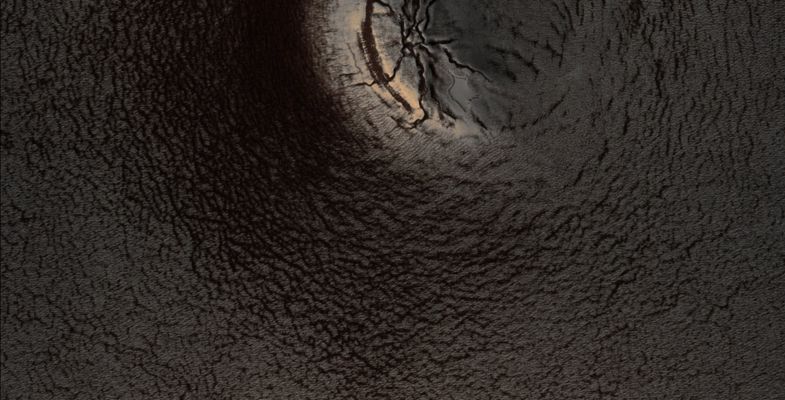 Icy Impact (EDM - Natural Colors; credits: Lunexit)
The Impact Crater in this image is roughly 900 meters (a little over 0,5 mile) across. 
The remaining Raised Rim of the Crater is illuminated from the bottom right of the image, causing preferential heating of the interior of the Rim structure. 
The ice appears thin here (more brown material is exposed), with an even thinner cover on the remaining exterior Rim. 
This could be caused by a number of possibilities: perhaps the Exterior Wall is steeper than the Interior Wall, resulting in more direct exposure to sunlight, causing more efficient sublimation when the Sun shines on that Wall.

Once ice begins to melt, darker dustier material is exposed. The darker material absorbs more heat than white ice (just like standing in the Sun wearing a black shirt makes you warmer than wearing a white shirt, which reflects the Sun's light), causing more and more ice to sublimate near the dark material.
Parole chiave: Mars from orbit - Craters - Unnamed Crater in the South Polar Region