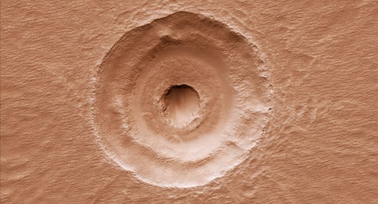 Bull's Eye Impact Crater (RAW Natural Colors; credits for the additional process. and color.: Elisabetta Bonora - Lunexit Team)
What caused the Central Pit within this Impact Crater: unusual Subsurface Layering or a lucky second impact? Impacts into layers of alternately strong and weak material – for example, ice rich versus non-ice-rich – produce terracing such as that seen between the Inner Pit and the Outer Rim. Scientists have used Terraced Craters to estimate the thickness of Lava Flows on the Moon and elsewhere. Uneven Sublimation and Periglacial Erosion of exposed ice-rich material in the interior of the Crater may explain why the small Central Pit is slightly offset from center relative to the Terrace and Rim of the larger Crater. 
The Pit in the center of the main feature could also be from a later Impact Crater striking inside and slightly off-center from the original. It has a Raised Rim, which is characteristic of impact craters and is difficult to explain with a layered target. While no ejecta from this later impact can be seen, the ejecta could have been removed by extensive periglacial modification. 
Additionally the Floor Fill around the Inner Crater resembles impact ejects elsewhere at this latitude, and some of the "Landslides" to the East could be flow-back of ejecta off the Walls of the larger crater.

Parole chiave: Mars from orbit - Craters - Unnamed Crater with "Bull's Eye" shape