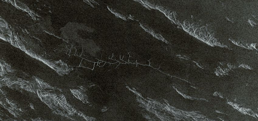 Complex Network of Narrow Fractures near Hestia Rupes Region (possible Natural Colors; credits: Dr Paolo C. Fienga - Lunexit Team)
This is a Magellan radar image covering an about 105- Km (approx. 63-mile) by 45-Km (approx. 27-mile) Region near Hestia Rupes on the North-Western corner of Aphrodite Terra. 

The complex network of narrow (such as <1 Km) Fractures in the center of the image extends for approx. 50 Km (about 31 miles). This network exhibits tributary-like branches similar to those observed in river systems on Earth. However, the angular intersections of the tributaries suggest tectonic control. 
These features appear to be due to drainage of lava along preexisting fractures and subsequent collapse of the Surface. The underlying tectonic fabric can be observed in the North-East trending Ridges which predate the Plains.
Parole chiave: Venus from orbit - Tectonic Fractures