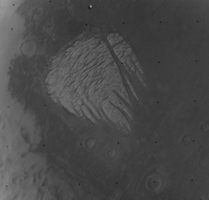 Pollack Crater and "White Rock" from Mariner 9 (RAW Frame - credits: NASA)
"...It was interesting to browse through the Mariner 9 data set to locate these images, because evidently the Mariner 9 Team wasn't sure to make of these strange bright deposits. 
The first one I posted was described as "white rock" in a comment on the image, and that name has stuck. But another image's descriptive comment read "curious ice patches". 
Another totally misidentified not only the nature but the location of the photo, describing it as "Polar Cap". 
Comments on images of other places in the Mariner 9 Catalog generally reflect the fact that Mars had not yet been systematically surveyed by an orbiter, so the scientists often weren't quite sure what they were looking at, and even when it was clear there were craters, those craters had mostly not yet been named. 
I came across comments like "peculiar filametary structure" and "possible craters" and "streaky detail" and "cloud?" and "multitude of surface detail" and "odd fork-shaped bright pattern." 

It's fun to browse through that table and imagine surveying Mars, with a spacecraft stationed at the Planet for the first time, made all the more dramatic by its initial obscuration by a dust storm that slowly cleared. 

Mariner 9 is one of the more challenging data sets to work with because it's just so old. However, everything you need to access it, find images, view them, and convert them to more familiar formats is readily available online. First of all, the data itself can be found by browsing the data volumes at the PDS Imaging Node, and you can learn a little bit about the data at the National Space Science Data Center. To figure out what's what and to try to track down images of specific areas, you can download this spreadsheet (XLS format, zipped, 7.5 MB) containing an index to all the images. 
The images are all in a format that won't be familiar to most of you, but like most spacecraft data you can convert a folder full of images to PNG format using my favorite amateur-produced software, Björn Jónsson's IMG2PNG. However, if you're only working with a couple of images, I'd recommend a different amateur-produced piece of software for converting the images, Piotr Masek's MarinerView, because MarinerView can be used to correct the Mariner 9 images (one at a time) for the little white specks of noise that are spattered across every one. 

I'm slowly working on tracking down images of "White Rock" taken by every mission. First Mariner 9, then the Viking orbiters, then Mars Global Surveyor's MOC, then Mars Odyssey THEMIS, then Mars Express HRSC, and, finally, I should be able to produce Mars Reconnaissance Orbiter views from three different instruments: HiRISE, CTX, and CRISM. Stay tuned for further installments...".

Emily Lakdawalla (Planetary Society)
Parole chiave: Mars from orbit - Craters - Pollack Crater