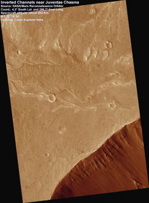 Inverted Channels Near Juventae Chasma
This image shows several long, sinuous features on the plains near Juventae Chasma. These features have been explained as former stream channels now preserved in inverted relief. 

Inverted relief occurs when a formerly low-lying area becomes high-standing. For instance, depressions may become filled with lava that is more resistant to erosion. In the case of stream channels, there are several possible reasons why the channel might stand out in inverted relief. The streambed may contain larger rocks, which remain while fine material is blown away by the wind, or it could be cemented by some chemical precipitating from flowing water. 

These features are old, since several impact craters cut the ridges. They provide important information about past processes on Mars. Understanding how streams could have formed is an important issue in understanding the history of water on Mars.
Parole chiave: Mars from orbit - Channels - Juventae Chasma Region