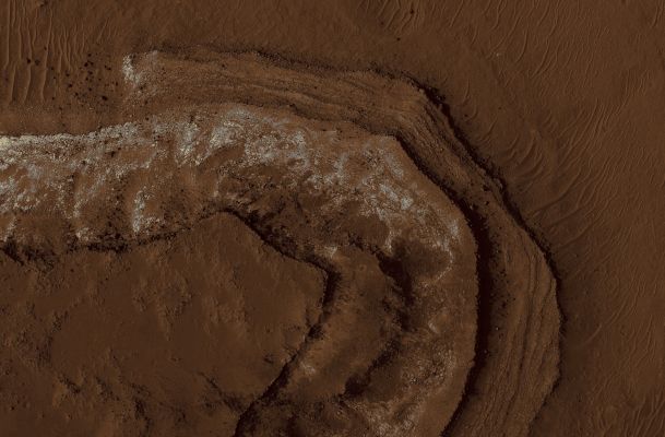 Layered Deposits in Ritchey Crater (edm - possible True Colors; credits: Lunar Explorer Italia)

This cutout from the top center part of the context image shows this stack. 
The dark unit is thin and breaking into boulders. The light material is actually divided into smaller layers, and is pervasively fractured. However, the boulders falling from the edge are mostly small and rarely remain intact if they move more than a few meters. 
The cracking of the layer could be due to water loss from the layer, or to regional tectonic effects such as stresses from burial and erosion. 
The base unit is partially covered by wind-blown ripples.
Parole chiave: Mars from orbit - Craters - Ritchey Crater