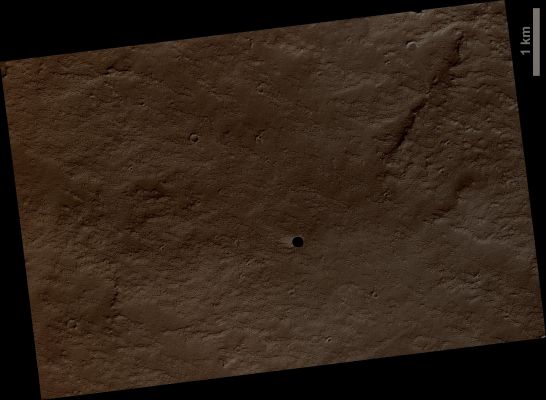 Canditate Cavern Entrance (CTX Frame - Absolute Natural Colors; credits for the additional process. and color.: Dr Paolo C. Fienga - Lunexit Team)
This image shows a very dark spot on an otherwise relatively bright dusty Lava Plain to the North-East of Arsia Mons, one of the four giant Tharsis volcanoes. 
This is NOT an Impact Crater as it lacks a Raised Rim or Ejecta Blanket. What's amazing is that we cannot see any detail in the shadow. The HiRISE camera is very sensitive and we can see details in almost any shadow on Mars, but not here. 
We also cannot see the deep walls of the Pit.  The best interpretation is that this is a Collapse Pit into a Cavern or at least a pit with Overhanging Walls. We cannot see the Walls because they are either perfectly vertical and extremely dark or, more likely, overhanging.
The Pit must be very deep to prevent detection of the floor from skylight, which is quite bright on Mars.
Parole chiave: Mars from orbit - Collapse Features - Cavern