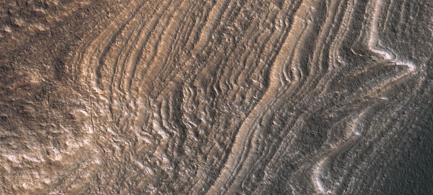 Distorted Layers in the SPLD (extra-detail mgnf - MULTISPECTRUM; credits: Lunexit)
This enhanced image (1,2 Km or 0.7 miles across) shows a section of the South Polar Layered Deposits, which are an accumulation of layers consisting mostly of water ice and dust. Perhaps their closest analog on Earth would be the Ice Caps of Greenland and Antarctica.

This image is particularly interesting because the layers are not flat-lying but rather appear "wavy" (---> ondeggianti). 
This appearance could partly be an “illusion” due to erosion after the flat-lying layers were deposited. In that case, the wavy appearance is due to the fact that the layer edges are wavy, going into and out of the plane of the outcrop exposing the layers.

Alternatively, this waviness could be due to deformation of the layers folding caused by flow of the ice. 
Here, the flow probably occurred long ago since current temperatures are too low to allow the ice to flow at a significant rate.
Parole chiave: Mars from orbit - South Polar Layered Deposits