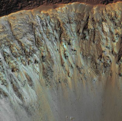 Colorful Layers in the Walls of an Unnamed Southern Crater  (extra-detail mgnf - MULTISPECTRUM; credits: Lunexit)
This extra-detail mgnf (enhanced to exaggerate color contrast) shows part of the North-facing walls of the crater, deeply carved by landslides. Rocky layers, mostly purplish in color, can be followed for hundreds of meters, poking through the loose materials that cover the slopes. 
Locally, the rocky layers show patches of diverse colors (blue, green, yellow). These colors may be indicative of compositional differences in the rocky layers.
Parole chiave: Mars from orbit - Craters - unnamed crater with layers and gullies