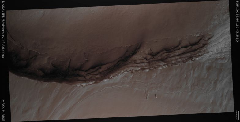 North Polar Layered Deposits (MULTISPECTRUM; credits: Lunexit)
The North Polar Layered Deposits of Mars form a layered stack of dusty ice up to 3 Km (about 2 miles) thick. The differences from layer to layer are thought to reflect differences in the climate of Mars that existed when the layers were formed.
We can see these internal layers exposed on the faces of the many troughs and scarps that cut through these deposits. 
One of these scarp faces is shown here; it is situated at the head of a large canyon (named Chasma Boreale) that cuts through these Polar Layered Deposits.
The terrain on the upper side of the picture is higher and consists of the upper surface of the icy layered deposits in this area while the terrain on the lower side of the frame consists of the rocky ground that underlies the layered deposits. The cliff that separates these two areas runs down the center of the image with a relief of about 700 meters (about 2300 feet).

The section of the Layered Deposits that is exposed on this cliff face is unusual in that, as well layers of dusty ice, there are also layers of sand present. Small structures, called cross-beds, visible in the sandy layers indicate that each layer was originally a dune field that only later became covered with ice. Some of this sandy material is being removed from the cliff face and is forming new dunes at the foot of the cliff.
Parole chiave: Mars from orbit - North Polar Region - Layered Deposits