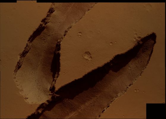 Echelon Fractures in Cerberus Fossae (Natural Colors; credits: Dr M. Faccin & Lunexit)
The colors visible in this Natural Colors image result from differences in composition of the materials existing in and around the fractures (which were likely caused by the shifting of Mars Crust -----> i.e.: Tectonic Fractures) and they DO represent how it would appear to the human eye. 
Note that one can make out boulders and small dunes at the bottom of these fractures and layering within the walls. 
Just visible at the top of the image is well-preserved impact crater ejecta. This image is about 1,2 Km across.
