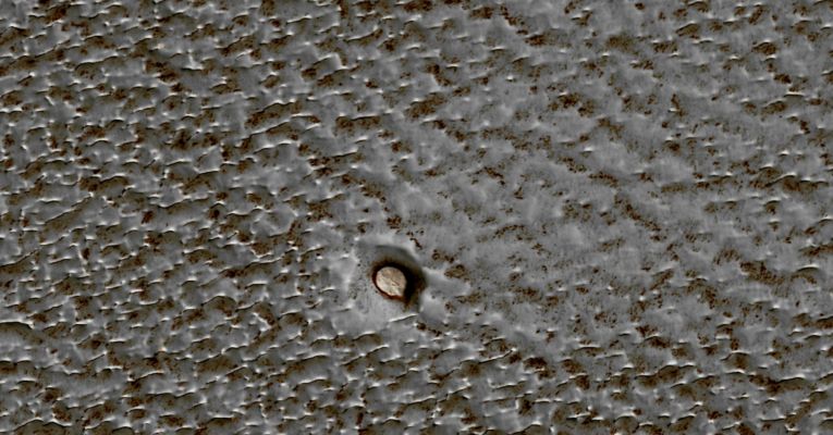 Small Crater on Planum Boreum (edm - natural colors; credits: Lunexit)
This edm frame shows an example of a rare, small crater (approx. 115 meters, or 125 yards, in diameter). Scientists can count these shallow craters to attain an estimate of the age of the upper few meters of the Planum Boreum Surface.

The colors come from the presence of dust and of ice of differing grain sizes. The blueish ice has a larger grain size than the ice that has collected in the crater. The reddish material is dust. The smooth area stretching to the upper right, away from the crater may be due to winds being channeled around the crater or to fine-grained ice and frost blowing out of the crater.
Parole chiave: Mars from orbit - North Polar Regions - Planum Boreum