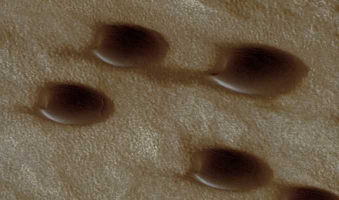 Dunes and other Surface Features in Chasma Boreale (edm n. 1 - possible True Colors; credits: Lunexit)
The sand dunes visible here are Barchan Dunes. 
Barchan Dunes are also commonly found on Earth, and are crescent-shaped with a steep slip face bordered by horns oriented in the downwind direction. Barchan Dunes form by uni-directional winds and thus are good indicators of the dominant wind direction. 
In this case, the dunes indicate that the direction of the strongest winds are parallel to the chasma walls, roughly East to West. The dark material composing the dunes could be volcanic ash or is possibly dark sand eroding out of the polar layered materials.
Parole chiave: Mars from orbit - North Polar Regions - Chasma Boreale
