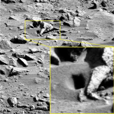 Rectangular Hole? - Sol 410 (by Dr Gianluigi Barca)
Un buco "rettangolare" su Marte? No, è una semplice illusione ottica determinata dal particolare angolo di ripresa, ove rapportato alla configurazione del suolo ed alla posizione del Sole nel Cielo di Marte. 
In realtà come si vede piuttosto bene nell'inset magnificato, si tratta di una modesta depressione a forma circolare, sulla quale insiste un'ombra netta e squadrata, determinata - nel suo lato inferiore e laterale Dx - appunto - dalla configurazione della superficie che la proietta e resa curiosamente affilata non solo dalla posizione del Sole nel Cielo Marziano (ancora molto alto, riteniamo), ma anche dalla scarsa definizione e qualità del frame.

Un ringraziamento al nostro Dr Barca per l'occhio, la curiosità e, ovviamente, lo "spunto" (perchè risolvere i piccoli misteri è, a nostro modo di vedere, estremamente formativo e di grande aiuto per poi affrontare e tentare di risolvere quelli Grandi...).
Parole chiave: Martian Surface - Light Trick
