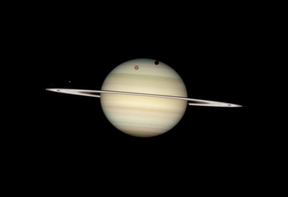The Ringed Beauty and (some of) His Companions (Natural Colors; credits: NASA)
Caption NASA:"On February 24, 2009, the Hubble Space Telescope took a photo of 4 moons of Saturn passing in front of their Parent Planet. In this view, the giant orange moon Titan casts a large shadow onto Saturn's North Polar hood. Below Titan, near the Ring-Plane and to the left is the moon Mimas, casting a much smaller shadow onto Saturn's equatorial cloud tops. Farther to the left, and off Saturn's disk, are the bright moon Dione and the fainter moon Enceladus.

These rare moon transits only happen when the tilt of Saturn's Ring-Plane is nearly "edge on" as seen from the Earth. Saturn's Rings will be perfectly edge on to our line of sight on August 10, 2009, and September 4, 2009. Unfortunately, Saturn will be too close to the Sun to be seen by viewers on Earth at that time. 
This "Ring-Plane Crossing" occurs every 14-15 years. In 1995-96 Hubble witnessed the Ring-Plane Crossing Event, as well as many moon transits, and even helped discover several new moons of Saturn.
The banded structure in Saturn's Atmosphere is similar to Jupiter's.
Early 2009 was a favorable time for viewers with small telescopes to watch moon and shadow transits crossing the face of Saturn. 
Titan, Saturn's largest moon, crossed (and shall cross) Saturn on 4 separate occasions: January 24, February 9, February 24, and March 12, although not all events were visible from all locations on Earth.

These pictures were taken with Hubble's Wide Field Planetary Camera 2 on February 24, 2009, when Saturn was at a distance of roughly 775 MMs (such as about 1,25 BKM) from Earth. Hubble can see details as small as 190 miles (such as about 300 km) across on Saturn. The dark band running across the face of the Planet slightly above the Rings is the shadow of the Rings cast on the Planet".
Parole chiave: Saturn