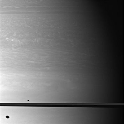 Shadows...
Caption NASA:"The shadows of two moons appear on Saturn, above and below the plane of the Planet's Rings. 
North on Saturn is up in this image, and the shadow of Dione can be seen south of the Planet's Equator. The smaller shadow of Mimas is north of the Equator. 
Dione and Mimas both have orbits that are slightly inclined in relation to the Planet's Equatorial Plane, so, depending upon the orientation of their orbits, their shadows may appear North or South of Saturn's Equator. The moons themselves do not appear in this image. 

This view looks toward the Northern, sunlit side of the Rings from about 1° above the Ring-Plane. Scale in the original image was about 100 Km (approx. 62 miles) per pixel. The image has been magnified by a factor of 1.5 and contrast-enhanced to aid visibility. 
The image was taken with the Cassini Spacecraft wide-angle camera on Oct. 15, 2009 using a spectral filter sensitive to wavelengths of Near-InfraRed Light centered at 752 nanometers. The view was acquired at a distance of approx. 899.000 Km (about 558.000 miles) from Saturn and at a Sun-Saturn-Spacecraft, or Phase, angle of 65°".
Parole chiave: Saturn