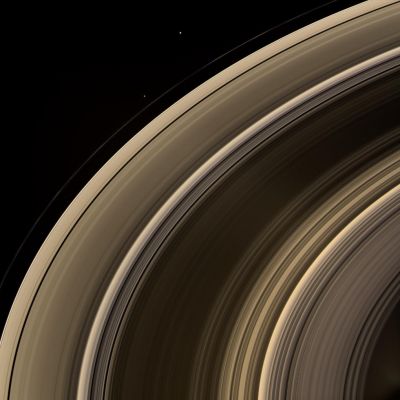 Rings and Companions (natural colors; credits: NASA)
Caption NASA:"From on high, the Cassini spacecraft spies a group of 3 Ring Moons in their travels around Saturn. Janus (181 Km, or 113 miles across) is seen at top, while Pandora (84 Km, or 52 miles across) hugs the outer edge of the narrow F-Ring. More difficult to spot is Pan (26 Km, or 16 miles across), which is a mere speck in this view. Pan can be seen in the Encke Gap, near center left. 
The speck seen between the A and F-Rings at left is a background star. 
This view looks toward the unilluminated side of the Rings from about 40° above the Ring-Plane. Images taken using red, green and blue spectral filters were combined to create this natural color view. 
Bright clumps of material in the narrow F-Ring moved in their orbits between each of the color exposures, creating a chromatic misalignment that provides some sense of the continuous motion in the Ring System. 

The images were obtained with the Cassini spacecraft wide-angle camera on Feb. 7, 2008 at a distance of approx. 1,1 MKM (about 700.000 miles) from Saturn. Image scale at the center of the view is roughly 74 Km (about 46 miles) per pixel in the radial, or outward from Saturn, direction".
Parole chiave: Saturn Rings