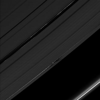 Shadows on the Islands...
Caption NASA:"The shadows cast by Daphnis' attendant edge waves create a dark, jagged pattern on the A-Ring in this image taken as Saturn approached its August 2009 Equinox. 

Daphnis (approx. 8 Km, or about 5 miles across) is a bright dot in the Keeler Gap of the A-Ring just below the center of the image. The moon has an inclined orbit, and its gravitational pull perturbs the orbits of the particles forming the Keeler Gap's edges and sculpts both edges into waves having both horizontal (radial) and out-of-plane components. Material on the inner edge of the gap orbits faster than the moon so that the waves there lead the moon in its orbit. Material on the outer edge moves slower than the moon, so waves there trail the moon. (See also PIA11656 to learn more about this process)

The novel illumination geometry that accompanies Equinox lowers the Sun's angle to the Ring-Plane, significantly darkens the Rings, and causes out-of-plane structures to look anomalously bright and cast shadows across the Rings. These scenes are possible only during the few months before and after Saturn's Equinox, which occurs only once in about 15 Earth years. Before and after Equinox, Cassini's cameras have spotted not only the predictable shadows of some of Saturn's moons (see also PIA11657), but also the shadows of newly revealed vertical structures in the Rings themselves (see, for example, the frame PIA11665). 
This view looks toward the Northern, unilluminated side of the Rings, from about 36° above the Ring-Plane. 

The image was taken in Visible Light with the Cassini Spacecraft narrow-angle camera on July 28, 2009. The view was obtained at a distance of approx. 1 MKM (about 621.000 miles) from Daphnis. 
Image scale is roughly 6 Km (a little less than 4 miles) per pixel".
Parole chiave: Saturn's Rings - "A" Ring