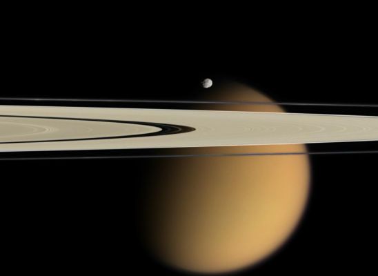 Hiding behind the Rings
Cassini delivers this stunning vista showing small, battered Epimetheus and smog-enshrouded Titan, with Saturn's A and F-Rings stretching across the scene. 
The color information in the colorized view is completely artificial: it is derived from red, green and blue images taken at nearly the same time and phase angle as the clear filter image. This color information was overlaid onto the previously released clear filter view in order to approximate the scene as it might appear to human eyes. 
The prominent dark region visible in the A-Ring is the Encke Gap (about 325 Km, or 200 miles wide), in which the moon Pan and several narrow ringlets reside. Moon-driven features which score the A-Ring can easily be seen to the left and right of the Encke Gap. 
A couple of bright clumps can be seen in the F-Ring. 
Epimetheus is 116 Km (72 miles) across and giant Titan is 5.150 kilometers (3.200 miles) across. 

The view was acquired with the Cassini spacecraft narrow-angle camera on April 28, 2006, at a distance of approx. 667.000 Km (about 415.000 miles) from Epimetheus and 1,8 MKM (about 1,1 MMs) from Titan. The image captures the illuminated side of the Rings. The image scale is roughly 4 Km (about 2 miles) per pixel on Epimetheus and about 11 Km (approx. 7 miles) per pixel on Titan.
Parole chiave: Saturn's Moons - Titan