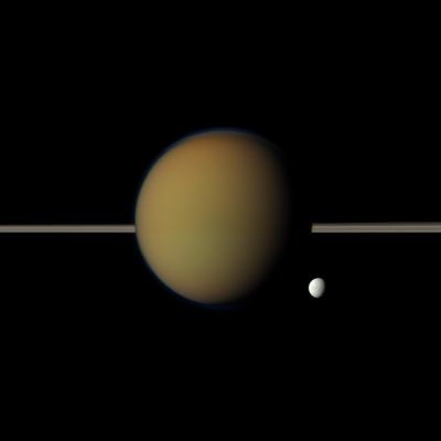 Titan and Tethys (Natural Colors; credits: NASA/JPL-Caltech/Space Science Institute)
Caption NASA:"Saturn's moon Tethys, with its stark white Icy Surface, peeps out from behind the larger, hazy, colorful Titan in this view of the two moons obtained by NASA's Cassini Spacecraft. Saturn's Rings lie between the two Celestial Bodies.
Ithaca Chasma, a long series of Scarps or Cliffs on Tethys, can be seen faintly running North-South.

This view looks toward the side of Titan that is facing away from Saturn and the side of Tethys that is facing Saturn. This view looks toward the Northern, sunlit side of the Rings from just above the Ring-Plane. Images taken using red, green and blue spectral filters were combined to create this Natural Color view. The images were acquired with the Cassini Spacecraft narrow-angle camera on May 21, 2011, at a distance of approx. 1,4 MMs (about 2,3 MKM) from Titan and approx. 2,4 MMs (such as about 3,8 MKM) from Tethys. Image scale is roughly 9 miles (approx. 14 Km) per pixel on Titan and roughly 18 miles (approx. 27 Km) per pixel on Tethys".
Parole chiave: Saturnian Moons - Titan and Tethys