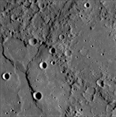 Ridges and Cliffs
Both it and the lighter-colored ridge that extends downward from it resemble wrinkle ridges that are common on the large Volcanic Plains, or "Maria," on the Moon. 
The MESSENGER science team is studying what features like these reveal about the interior cooling history of Mercury.

Ghostly remnants of a few craters are seen on the right side of this image, possibly indicating that once-pristine, bowl-shaped craters (like those on the large crater’s floor) have been subsequently flooded by volcanism or some other plains-forming process.
A complex history of geological evolution is recorded in this frame from the Narrow Angle Camera (NAC), part of the Mercury Dual Imaging System (MDIS) instrument, taken during MESSENGER’s close flyby of Mercury on January 14, 2008. 
Part of an old, large crater occupies most of the lower left portion of the frame. An arrangement of ridges and cliffs in the shape of a "Y" crosses the crater’s floor. 
The shadows defining the ridges are cast on the floor of the crater by the Sun shining from the right, indicating a descending stair-step of plains. The main, right-hand branch of the "Y" crosses the crater floor, the crater rim, and continues off the top edge of the picture; it appears to be a classic “lobate scarp” (irregularly shaped cliff) common in all areas of Mercury imaged so far. These lobate scarps were formed during a period when Mercury’s crust was contracting as the planet cooled. In contrast, the branch of the Y to the left ends at the crater rim and is restricted to the floor of the crater. 
This image was taken 18 minutes after close approach, when MESSENGER was about 5000 Km (about 3000 miles) away from Mercury. 
The image is about 200 Km (approx. 125 miles) across, and features as small as about 400 mt (about 400 yards) can be resolved. 
Parole chiave: Mercury Fly-By
