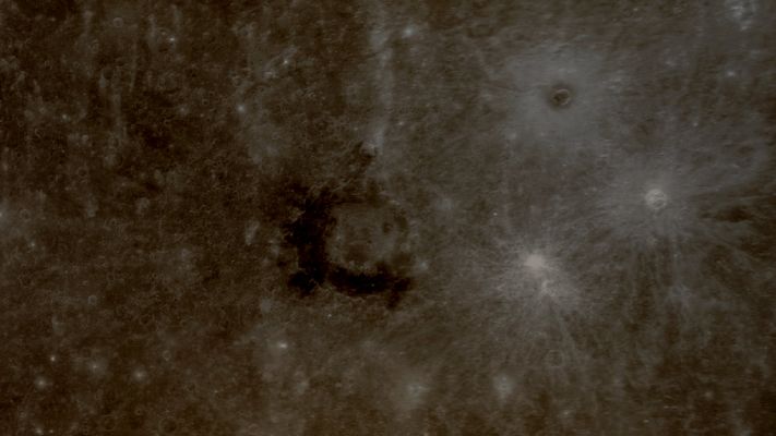 Dark Spot at "Derain Crater" (Enhanced Absolute Natural Colors; credits for the additional process. and color.: Dr Paolo C. Fienga - Lunexit Team)
In the center of this image is Derain, an impact crater first viewed during MESSENGER's 2nd Mercury flyby and named in 2009. 

Derain has material within it and in its surroundings that is much darker than the neighboring terrain. In fact, the material associated with Derain appears to have the lowest reflectance yet identified on Mercury's Surface. 
The Dark Deposits may be material with a mineralogical composition different from the majority of Mercury's visible Surface, but more data are needed before any further insight into the composition can be gained. 

Observations to be acquired during MESSENGER's orbital mission phase will help to identify the uncommonly Dark Material at Derain Crater and similar occurrences elsewhere on the Planet.

Also visible in this image (upper right side), is the rayed Crater "Berkel", which has Dark Material as well in its center and in a ring immediately surrounding it. In contrast, two neighboring craters of Berkel have bright rays but lack Dark Halos. Why do some craters contain Dark Materials while others do not? MESSENGER's orbital data will be used to investigate that question and to improve our understanding of the nature and structure of Mercury's Crust.

Date Acquired: October 6, 2008
Instrument: Narrow Angle Camera (NAC) of the Mercury Dual Imaging System (MDIS)
Scale: Derain Crater is approx. 190 Km in diameter (such as about 118 miles)
Parole chiave: Mercury's Fly-by