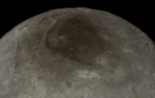 The Dark North Polar Regions of Charon  (Absolute Natural Colors; credits for the additional process. and color.: Dr Paolo C. Fienga - Lunexit Team)
As you can see very well here, in today's APOD, remarkable new details of Pluto's largest moon Charon are revealed in this wonderful Extra Detail Magnification (or "EDM", for short) that shows us the North Polar Regions of Charon itself - the original Contextual Picture was taken from the New Horizons' Long Range Reconnaissance Imager (or "LORRI", for short), late on July 13, 2015, from a distance of about 289.000 miles (such as approx. 465.099,26 Km) from the Surface of this - however - unusually-looking Celestial Body.
Generally speaking, the Mission Scientists are surprised by the apparent lack of Impact Craters on Charon. But, in particular, all over Charon's North Polar Regions (that is VERY WELL seen here), a dark marking - which was already prominent in the NASA - New Horizons Spacecraft' approach images - is now showing a diffuse (---> lighter in color) Boundary, suggesting that it could be a (thin?) Deposit of Dark Material (whose nature and origin are still - and, maybe, will remain - unknown). 
So, what are we talking about? A North Polar Cap made out of Frozen Hydrocarbons? Or, perhaps, a Layer of a powdered dark mineral - like Coal - which, eons after eons, fell over a Surface of bright Water Ice North Polar Cap and then turned its color (almost) completely black? Who knows...

The image has been compressed to reduce its file size for transmission to Earth. In high-contrast areas of the original Contextual Image, Surface Features as small as about 3 miles (approx. 4,828 Km) across can be seen. Some lower-contrast detail is obscured by the compression of the image, which may make some areas appear smoother than they really are. The uncompressed version still resides in New Horizons' Computer Memory and is scheduled to be transmitted at a later date. Remember that the NASA - New Horizons Spacecraft traveled more than three billion miles over nine-and-a-half years to reach the Plutonian System.

The image (which is a crop taken from an Original NASA - New Horizons Spacecraft's falsely colored and NON Map-Projected frame published on the NASA - Planetary Phojournal with the ID n. 19709) has been additionally processed, magnified to aid the visibility of the details, contrast enhanced and sharpened, Gamma corrected and then re-colorized (according to an educated guess carried out by Dr Paolo C. Fienga-LXTT-IPF) in Absolute Natural Colors (such as the colors that a normal human eye would actually perceive if someone were onboard the NASA - New Horizons Spacecraft and then looked ahead, towards the Plutonian moon Charon), by using an original technique created - and, in time, dramatically improved - by the Lunar Explorer Italia Team.
Parole chiave: Pluto's moons - Charon